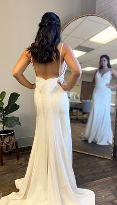 the back of a woman's wedding dress in front of a mirror with her reflection