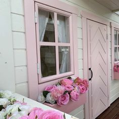 pink and white flowers are in the window sill next to some windows with shutters