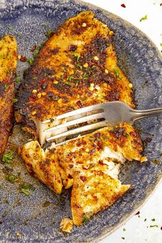 there is a fork that is on top of some chicken breast pieces in a blue plate