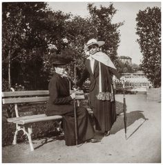 an old black and white photo of two people sitting on a bench next to each other