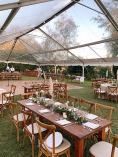 tables and chairs are set up under a tent for an outdoor wedding reception in the grass