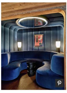 a room with blue couches and two lamps on the wall, in front of a circular mirror