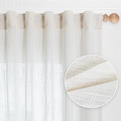 a white curtain hanging on the wall next to a round window sill with curtains