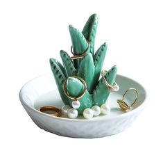 a white bowl filled with jewelry on top of a table next to a ring holder