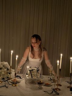 a woman standing in front of a table with candles