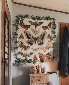 a wall hanging with moths on it next to a dresser and coat rack in a room