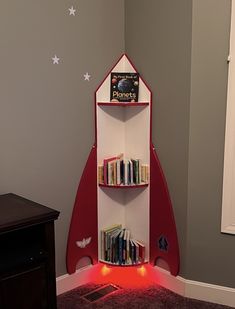 a red and white book shelf with books on it in a child's room