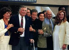 a group of people standing next to each other in front of a building with a sign