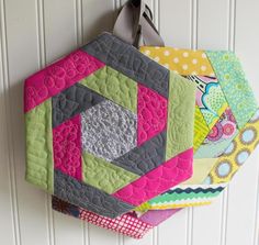 several colorful quilts hang on a white wall and are hanging from the side of a door