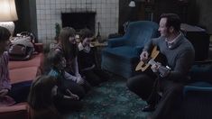 a group of people sitting around each other in a living room with guitars on the floor