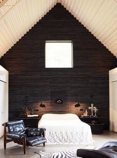 a bedroom with black and white decor on the walls, leather chairs and a bed