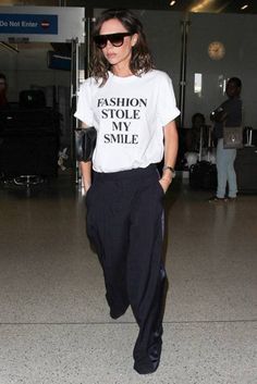 a woman wearing a t - shirt that says fashion stole the smile while walking through an airport