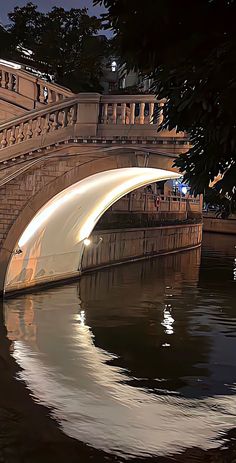 a bridge that is over some water with lights on at the top and below it