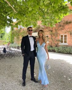 a man in a tuxedo standing next to a woman in a blue dress