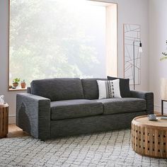 a living room with a gray couch and table in front of a large open window