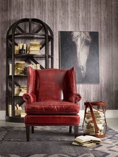 a red leather chair sitting in front of a book shelf with books on top of it