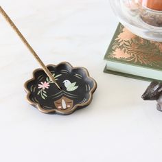 a small black flower shaped dish sitting on top of a table next to a candle holder