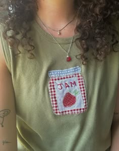 a woman wearing a green shirt with a red and white checkered pocket on her chest