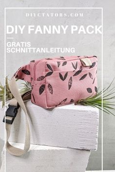 the diy fanny pack in pink with black leaves is sitting on top of a white block