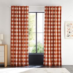 an orange and white checkered curtain hangs in front of a window with a potted plant