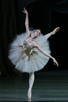 the ballerina is dressed in white and gold