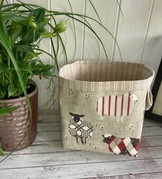 a potted plant sitting next to a basket with sheep on it and another potted plant in the background