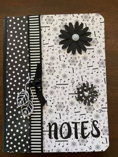 an open notebook with black and white paper on it, decorated with polka dots and a flower