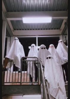 several people dressed in white are walking up the stairs with ghost costumes on their heads