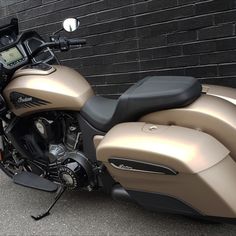 a gold motorcycle parked in front of a brick wall with a digital clock on it