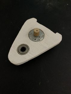 a white object sitting on top of a black table next to a metal ball bearing