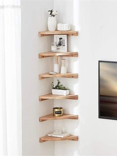 three wooden shelves in the corner of a room with white walls and paintings on the wall