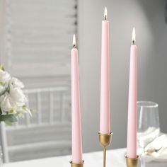 three pink candles sitting on top of a white table