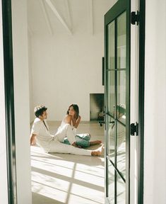 two people are sitting on the floor in an open room, one is talking to the other