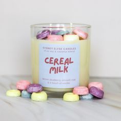 a jar filled with candy covered candies sitting on top of a table next to a candle