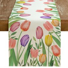 a table runner with watercolor tulips painted on it and green grass in the background