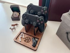 two video game controllers are on a wooden stand next to other items and a clock