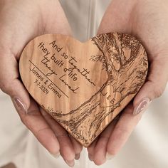 two hands holding a wooden heart shaped plaque with the words and image of a tree