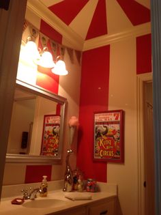 the bathroom is decorated in red and white with circus posters on the wall above the sink