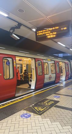 a red and white train is pulled up to the platform at an empty subway station