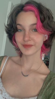 a woman with pink hair is smiling at the camera