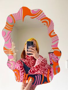 a woman taking a selfie with her cell phone in front of a colorful mirror