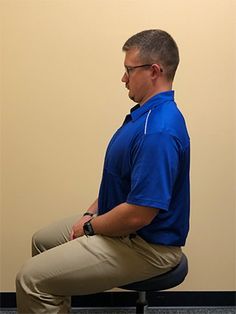 a man sitting on top of a chair in front of a wall