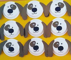 paper plates with dog faces on them sitting on a yellow tableclothed surface, ready to be eaten