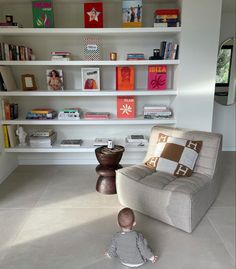 a baby sitting on the floor in front of a bookshelf filled with books