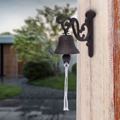 a bell hanging from the side of a wooden building with a metal hook on it