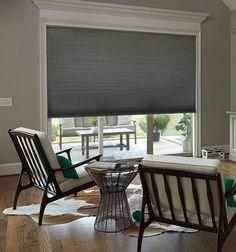 a living room filled with furniture and a window covered in roman blind shades on the windowsill