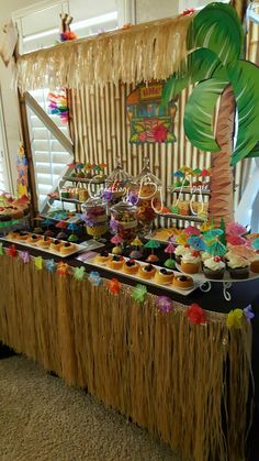 a table filled with cupcakes under a palm tree