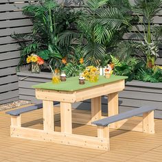 a wooden table with benches in front of plants