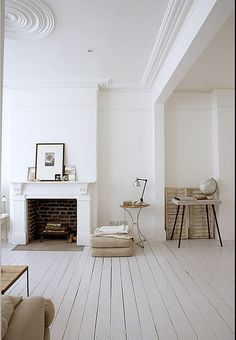 a living room with white walls and wood floors, including a fireplace in the center