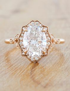 an oval cut diamond ring on top of a wooden table